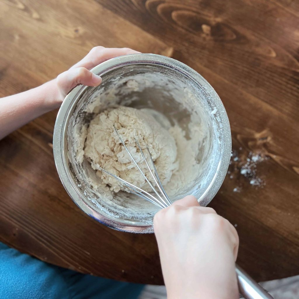 A child mixes the ingredients for fried bannock bread together in a mixing bowl. 