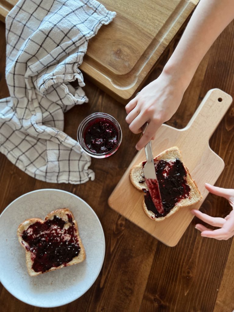 A child spreads wild blueberry jam on toast as part of a Canada unit study after reading Wild Berries by Julie Flett.