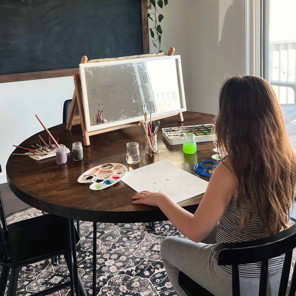 A child paints a self portrait during a Frida Kahlo artist study as part of the Global Explorers Club's Mexico unit study, an "Around the World" geography homeschool curriculum